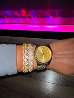 Gold watch and smiling face bracelets on a wrist