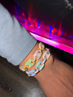 Close-up of a wrist wearing a two mariner link  bracelet with a vibrant background.