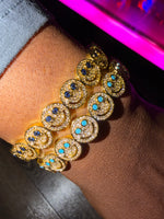 Gold smiley bracelet with blue stones on a wrist 