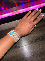 Hand wearing a stack of luxury green and  blue clover bracelets 