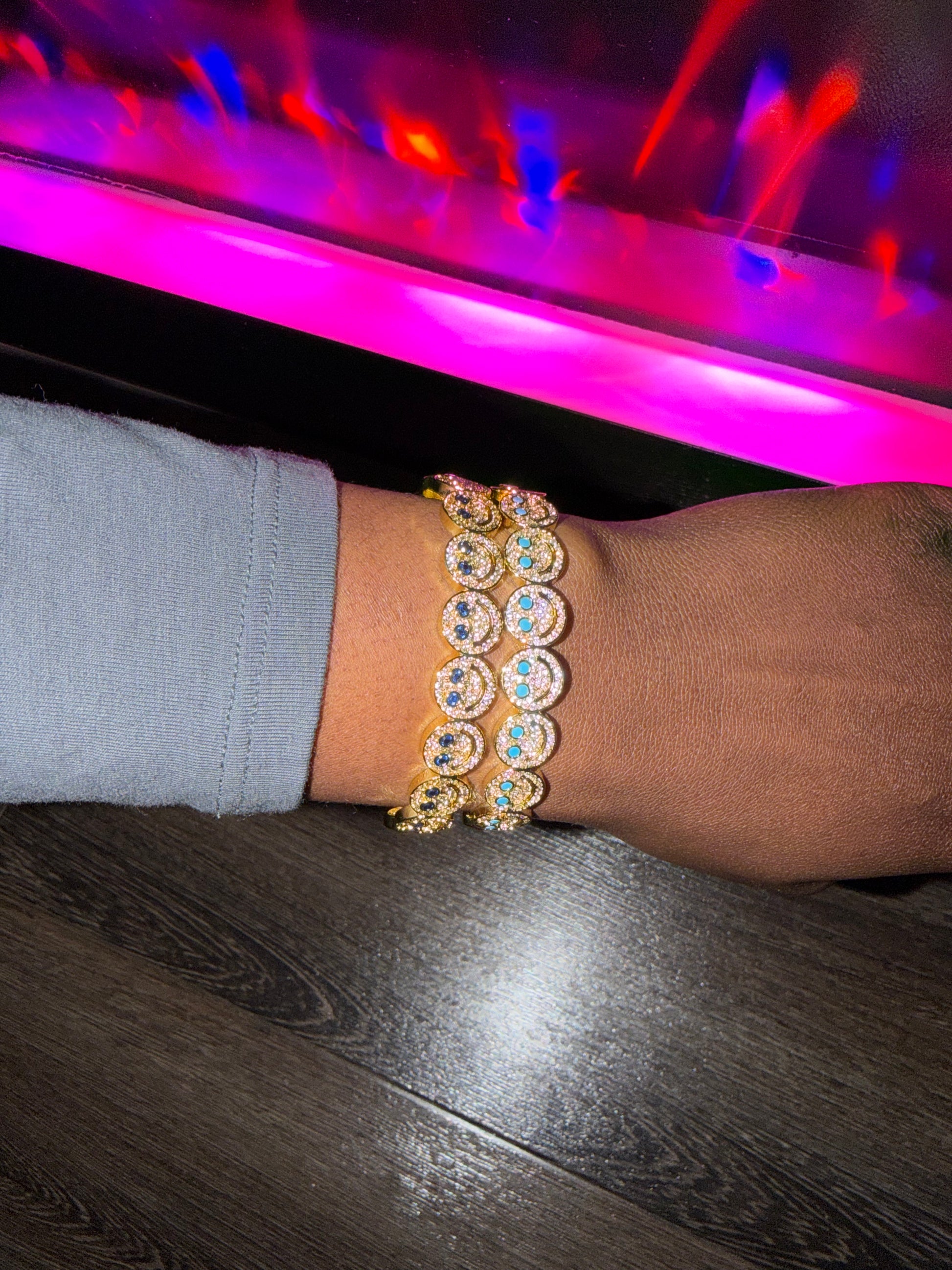 Person wearing multiple smiley face diamond bracelets.
