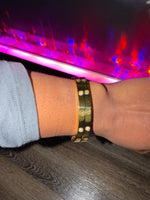 Person wearing a gold bracelet with small stones.