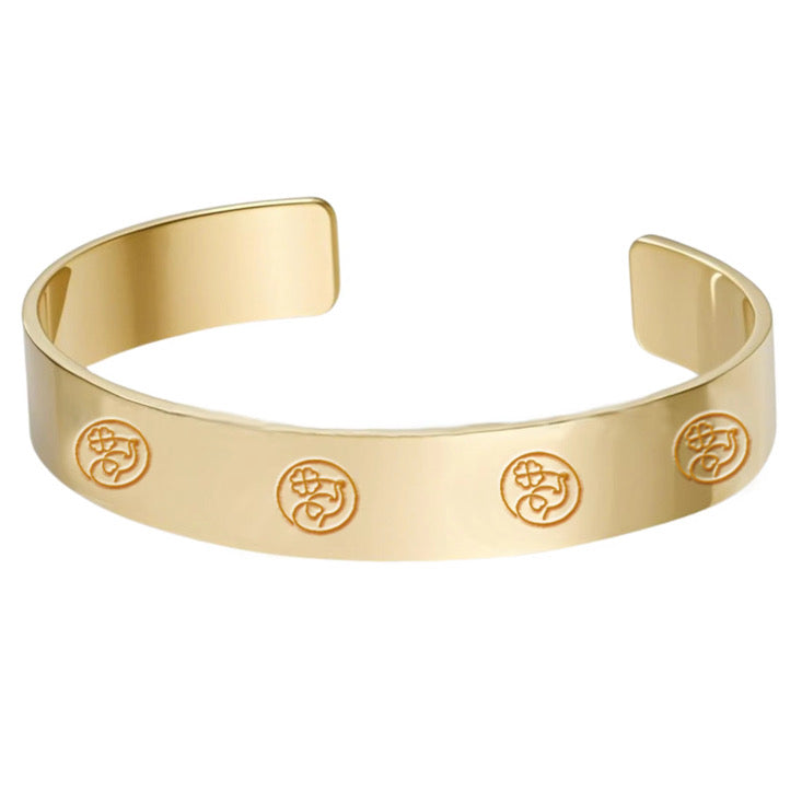 Gold bracelet with engraved symbols on a white background