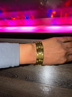 Hand wearing a gold bracelet  with single diamond loved by many with colorful lights in the background