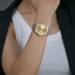 A Swiss designed So Italy Two Tone Watch with a gold sunray dial, classic five link gold and silver mixed metal bracelet, and a magnified date window model by a lady.