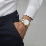 male model wearing A gold luxury watch with a mother of pearl dial and a classic fluted bezel and diamond markers.
