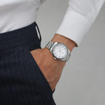 A silver luxury watch with a mother of pearl dial and a fluted bezel worn by a modern male.