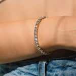 A close-up image of a person's wrist wearing a diamond tennis bracelet