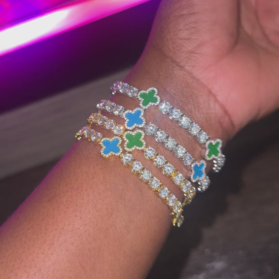 Stack of four blue and green clover bracelets in gold and silver on wrist